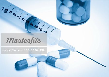 Pills with medicine box and syringe against a white background