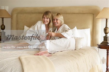 Two Women Enjoying Champagne In Bedroom