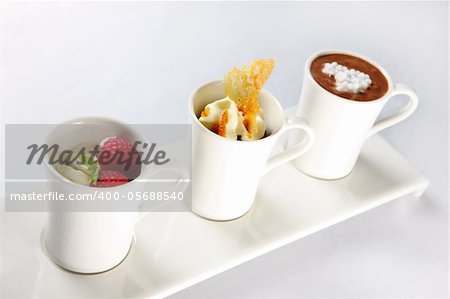 A picture of three different desserts in mugs over white background