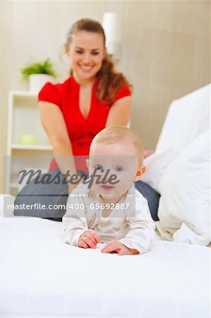 Smiling mother and adorable baby playing on sofa