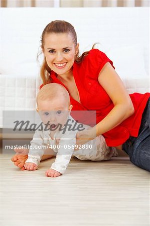 Happy mother and lovely baby playing on floor