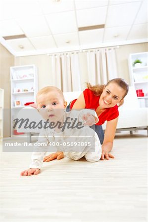 Smiling mommy playing with creeping on floor baby
