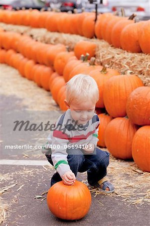 adorable caucasian toddler picking up a pumpkin