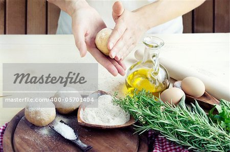 Woman is kneading dough balls for pizza or pastry, pasta preparation in the bakery . Ingredients for dough: Olive oil, salt and herbs with flour