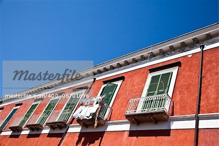 Detail of an ancient red house with a blue sky background in Procida Isle, Italy