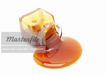 Honey spill from a glass jar isolated on white