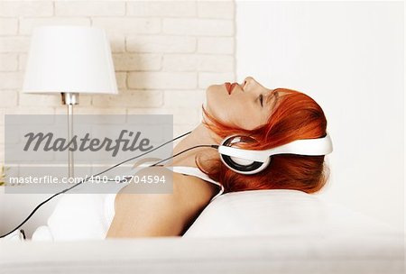 Caucasian redhead woman wearing headphones and listening music