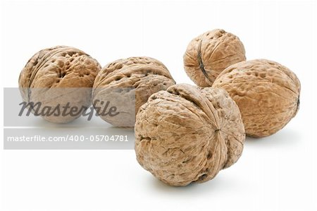 Arrangement of five whole walnuts close-up isolated on white background.
