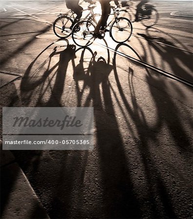 Silhouette of cyclists at sunrise, casting long shadows