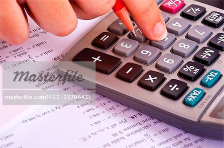 Student doing maths exercices with a calculator and a red pencil.