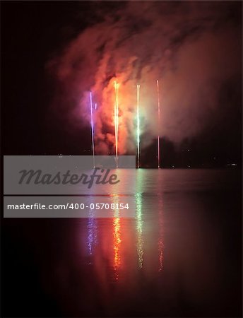 Colorful fireworks on black sky background with water reflections