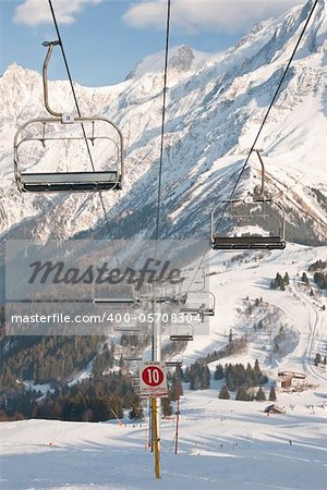Four chair lifts on the Alps background.