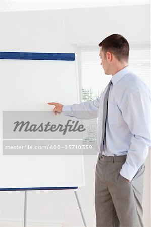 Confident businessman pointing at the middle of a flip chart