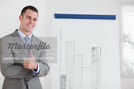 Smiling businessman giving thumb up next to diagram