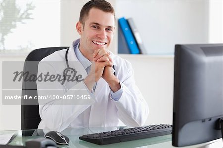 Smiling young doctor sitting at his desk