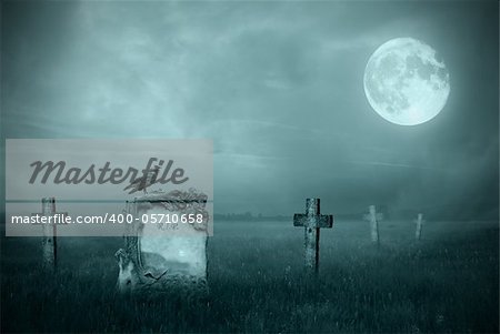 Crow sitting on a gravestone in moonlight