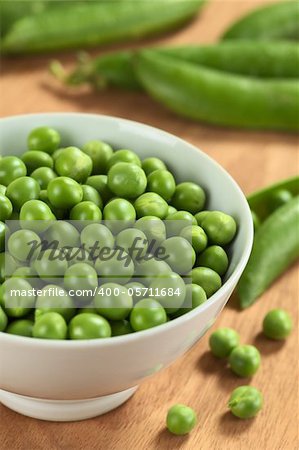 Fresh raw green pea (lat. Pisum Sativum) in white bowl (Selective Focus, Focus on the peas in the middle of the bowl)