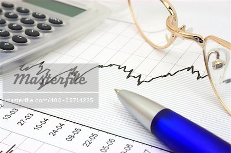 Stock chart with calculator, blue pen and eyeglasses