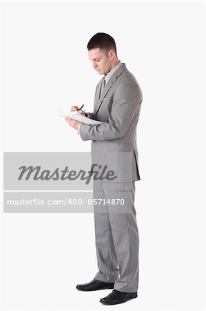Portrait of a serious businessman taking notes against a white background