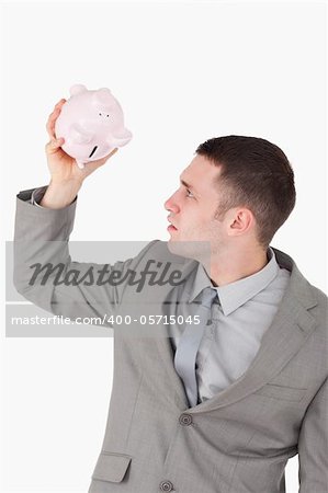 Portrait of a businessman looking in a piggy bank against a white background