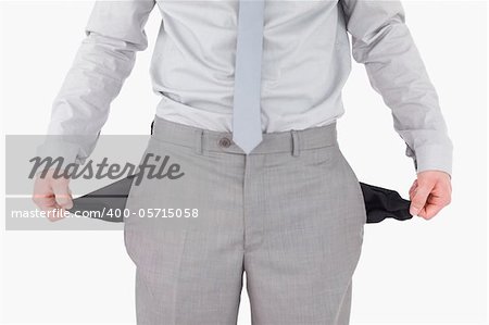 Businessman showing his empty pockets against a white background