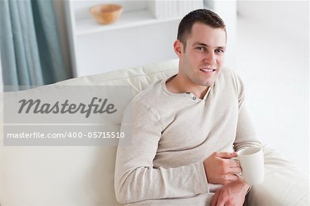 Attractive young man having a coffee in his living room