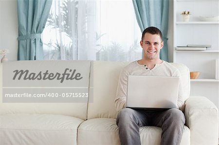 Man using a laptop while sitting on a sofa in his living room