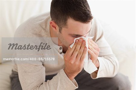 Ill man blowing his nose in his living room