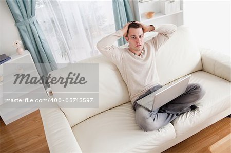 Sad man relaxing with a notebook in his living room