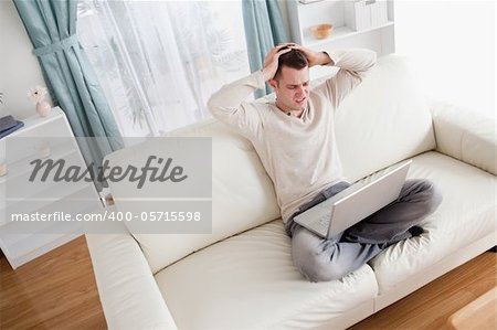 Unhappy man using a notebook in his living room