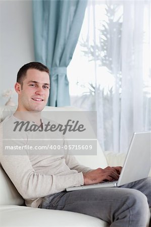 Portrait of a happy man typing on his notebook in his living room