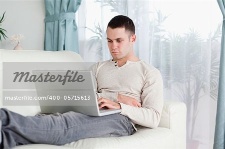 Young man working with his laptop in his living room