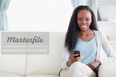 Smiling woman typing a text message on the sofa
