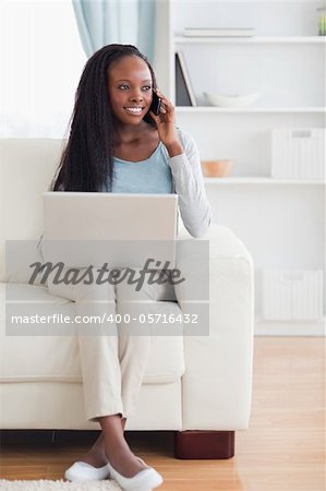 Smiling woman with cellphone and laptop on the sofa