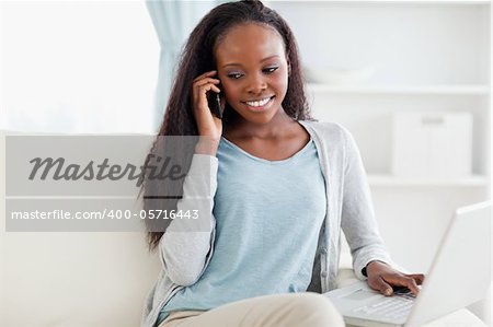 Smiling woman on sofa with laptop and smartphone