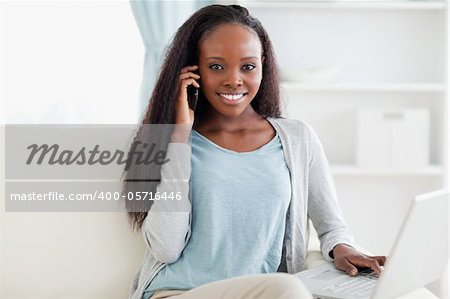 Smiling woman on sofa with notebook and smartphone