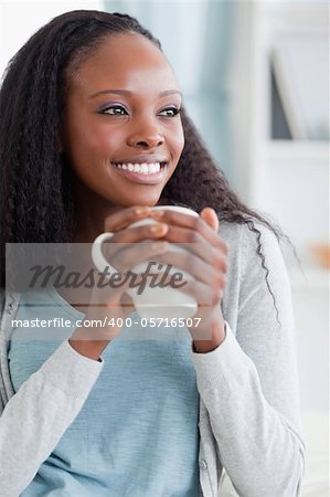 Close up of smiling woman having a coffee on sofa