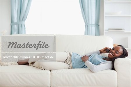Smiling woman lying on couch with cellphone