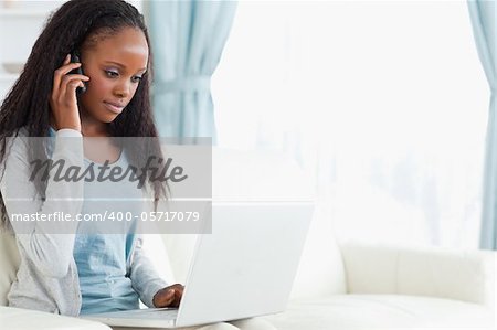 Young woman on the phone while using laptop