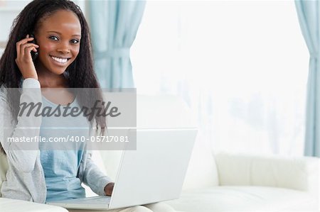 Smiling young woman on the phone while working on laptop