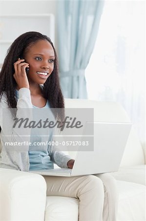Smiling woman on her phone while using laptop