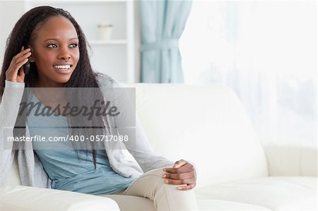 Smiling woman sitting on couch while using her phone