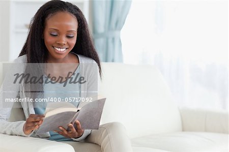 Smiling woman on sofa with book