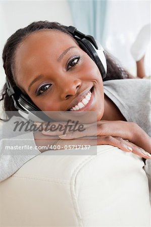 Close up of smiling woman enjoying music on her sofa
