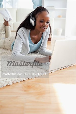 Close up of young woman lying on floor with her notebook enjoying music