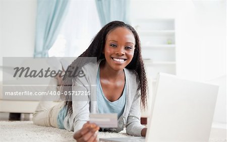 Smiling woman lying on the floor with her notebook shopping online