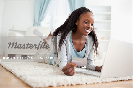 Smiling woman lying on floor with her laptop shopping online