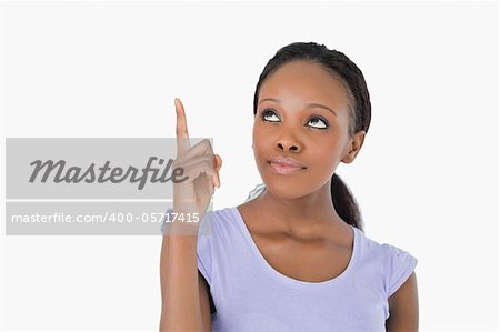 Close up of young woman pointing upwards on white background