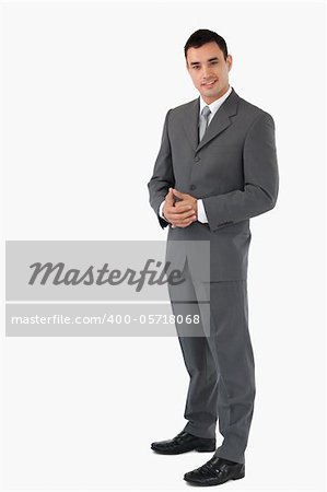 Young confident businessman with hands folded against a background