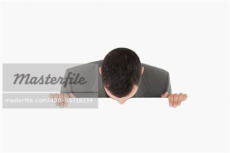 Businessman looking down on sign against a white background